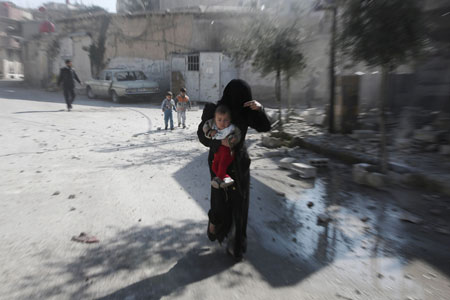 Una mujer camina con su hijo en brazos en las afueras de Damasco, Siria. Amer Almohibany/AFP/Getty Images
