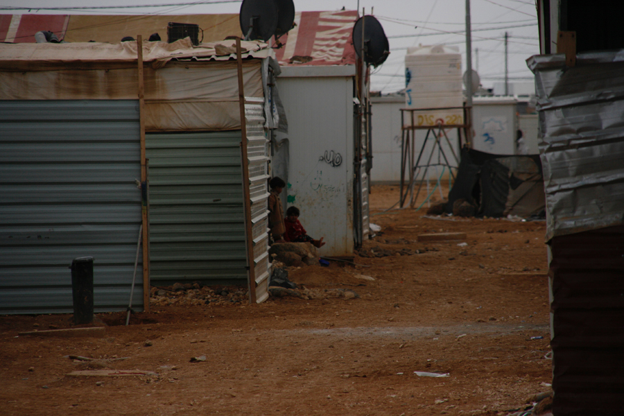Uno de los mayores problemas es la cantidad de menores que viven en Zaatari. La mitad de los refugiados no superan los 18 años. A medida que se cruza el campo uno no tarda en percatarse de la cantidad de bebés y niños que han nacido allí. En la imagen, niños en la puerta de su alojamiento en una calle secundaria del campo. (Jacobo Morillo)