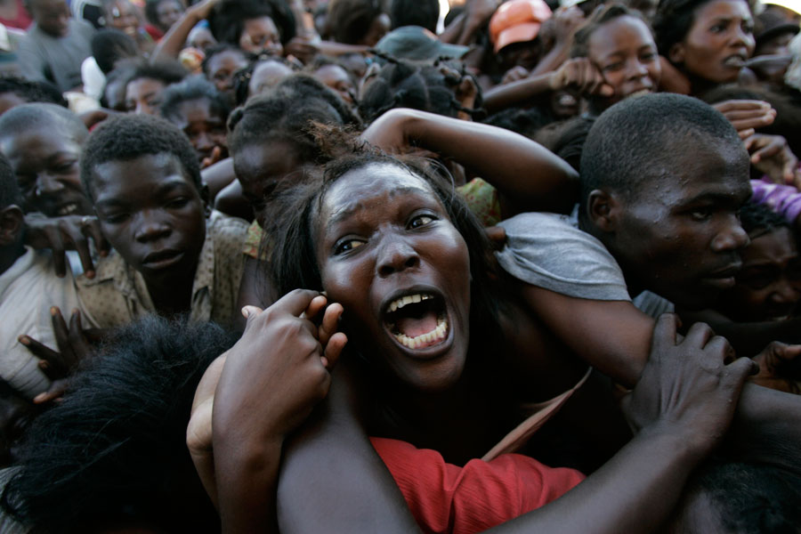Una mujer grita sofocada entre una multitud frenética, durante una operación de reparto de alimentos tras el terremoto, en Ciudad del Sol, barrio bajo de Puerto Príncipe. Haití, 14 de noviembre de 2002. © Ariana Cubillos/AP