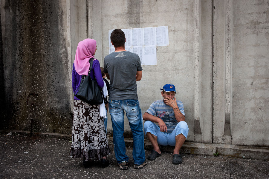 Una familia busca en una lista, colocada a la entrada de una nave en Potočari, el nombre de un familiar muerto. Fue en esta misma nave, custodiada por 'cascos azules' holandeses, donde el Ejército serbobosnio cometió la matanza de Srebrenica. © Mikel Oibar