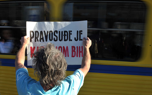 Un hombre bosnio sostiene un cartel que reza "el sistema judicial es el cáncer de Bosnia y Herzegovina". Elvis Barukcic/AFP/Getty Images