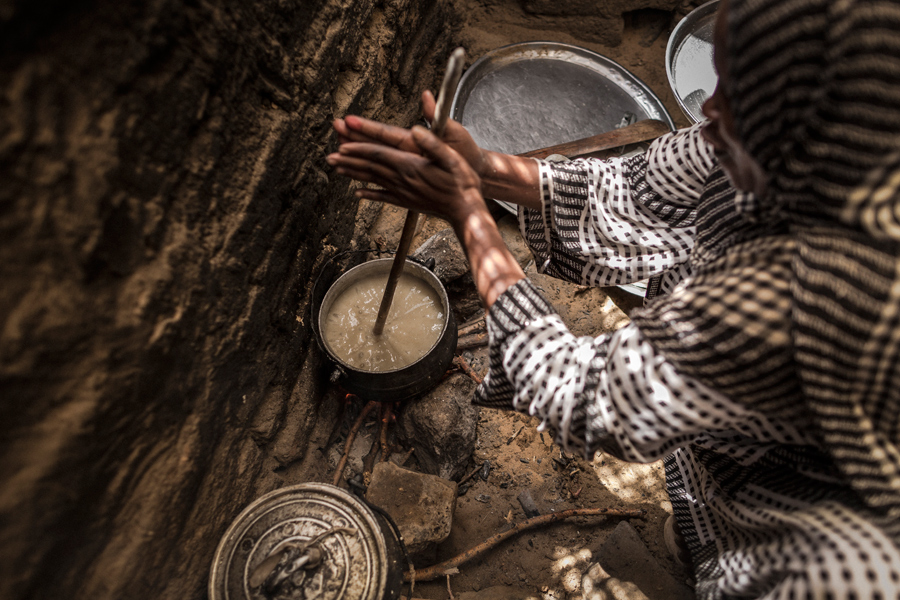 Las condiciones climáticas de Chad son extremas, desde la sequía a las lluvias torrenciales e inundaciones. El territorio se caracteriza por la erosión del suelo y la desertificación. En la foto Achta aparece cocinando en su choza para su familia. © Programa Mundial de Alimentos/Chris Terry, con el apoyo de la UE.