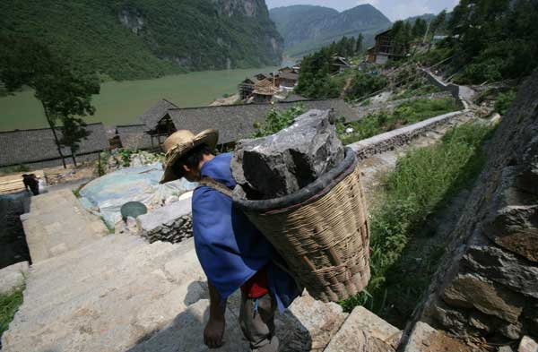 Entre los millones de desplazados por los proyectos hidráulicos de China se encuentran los 22.000 antiguos habitantes del distrito de Gongtan, en el municipio de Chongqing. El pueblo, de 1.700 años de antigüedad, contenía muestras de arquitectura residencial antigua que eran de las mejor conservadas en la región del río Yangtsé. Gingtan quedó completamente sumergido con la construcción de la central hidroeléctrica de Pengshui en el río Wujiang, un afluente del Yangtsé. Se reconstruyó a poco más de un kilómetro de distancia. En la foto, un obrero transporta piedras para reconstruir varias residencias tradicionales el 28 de julio de 2008. Algunas estructuras del pueblo original, como el diaojialou, un edificio tradicional sostenido por columnas de madera, fueron reedificadas en el nuevo, que se abrió a los turistas en 2009. Getty Images