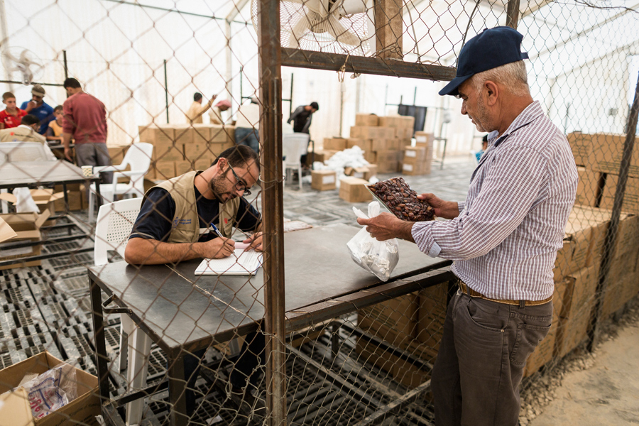 En Jordania, Abu Sayid recoge sus raciones de comida en el centro de distribución del Programa Mundial de Alimentos. Las raciones complementan el pan fresco que los refugiados sirios reciben diariamente en Zaatari. También les dan cupones con los que pueden adquirir otros productos en las tiendas del campamento. Este sistema también contribuye a la economía local. © Programa Mundial de Alimentos/Chris Terry, con el apoyo de la UE.
