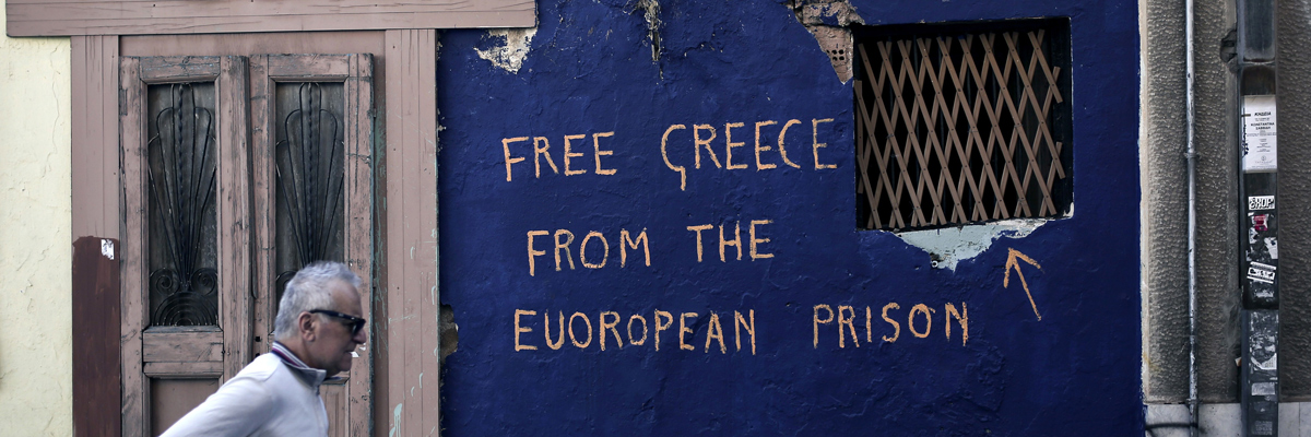 Un hombre camina al lado de un graffiti que dice "Liberar a Grecia de la prisión europea" en Atenas, junio de 2015. Angelos Tzortzinis/AFP/Getty Images