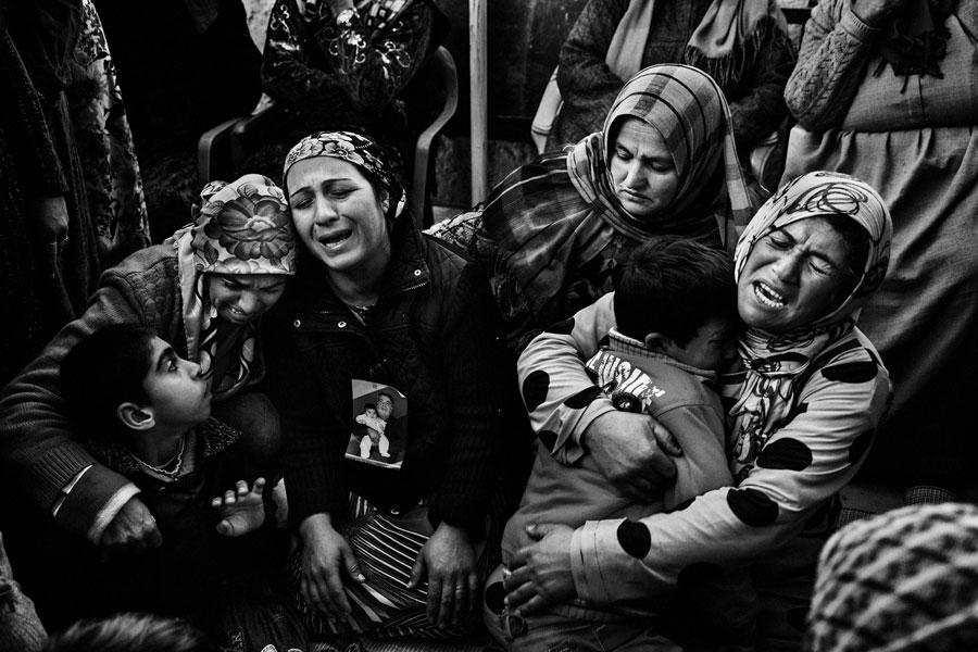 Los familiares de una mujer kurda que falleció después de visitar la tumba de su hijo, muerto a manos de los yihadistas en Srekaniye, lloran en su casa. Siria, 31 de diciembre de 2012. © Guillem Valle/Me-Mo Mag