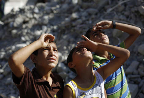 Niños palestinos miran un avión israelí en Beit Lahia, norte de la Franja de Gaza, agosto 2014. Mohammed Abed/AFP/Getty Images