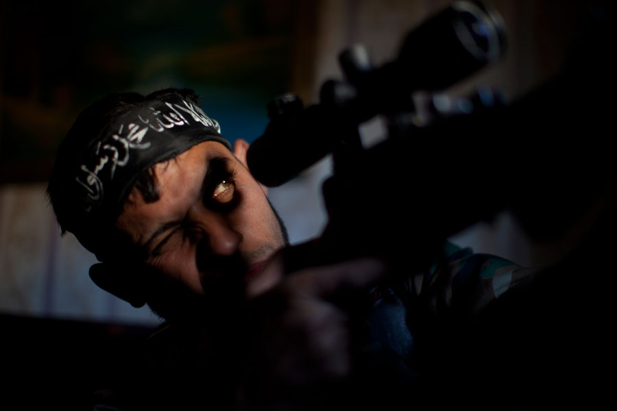 Abu Sufien, un joven de 30 años, apunta con su arma buscando un objetivo dentro de un edificio destruido en el barrio de Izaa en Alepo. El levantamiento popular de Siria comenzó con manifestaciones pacíficas y se fue convirtiendo, poco a poco, en una sangrienta guerra civil. Siria, 30 de diciembre de 2012. © J. M. López