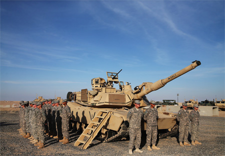 US troops stand to attention next to an Abrams tank as they wait for the arrival of US Secretary of Defence Chuck Hagel (unseen) for his visit to Camp Buehring in the northwest of Kuwait, roughly 65 miles from the Iraqi border, on December 8, 2014. Secretary Hagel visited the camp which once was a staging post for troops headed to Iraq. AFP PHOTO / MARK WILSON / POOL (Photo credit should read MARK WILSON/AFP/Getty Images)