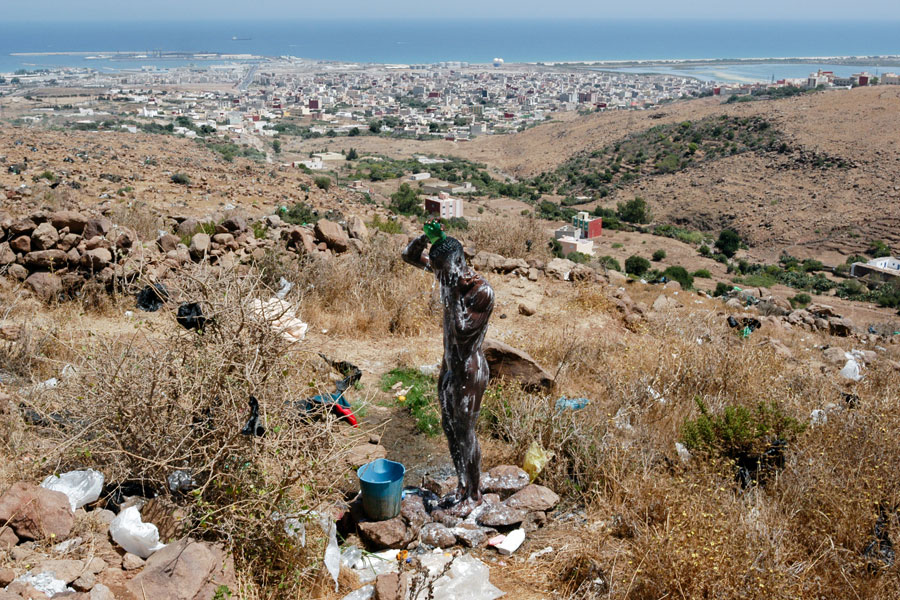 Un emigrante se asea en un campamento del Monte Gurugú, mientras espera lograr alcanzar Melilla, al fondo a la izquierda (junto a la localidad marroquí de Beni Enzar), y con ello España. Marruecos, 21 de agosto de 2004. © Luis de Vega
