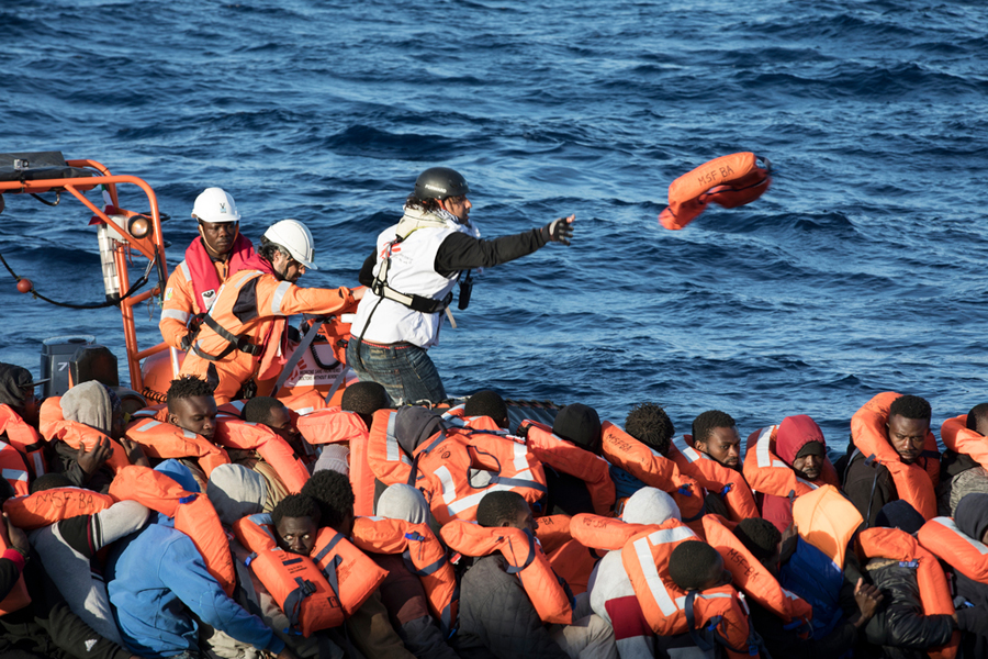 El mediador cultural de MSF y el equipo de Vos Prudence asisten a un bote en peligro con 130 personas a bordo de la embarcación de MSF, distribuyendo chalecos salvavidas antes de proceder a su rescate. Imagen de Albert Masias/MSF