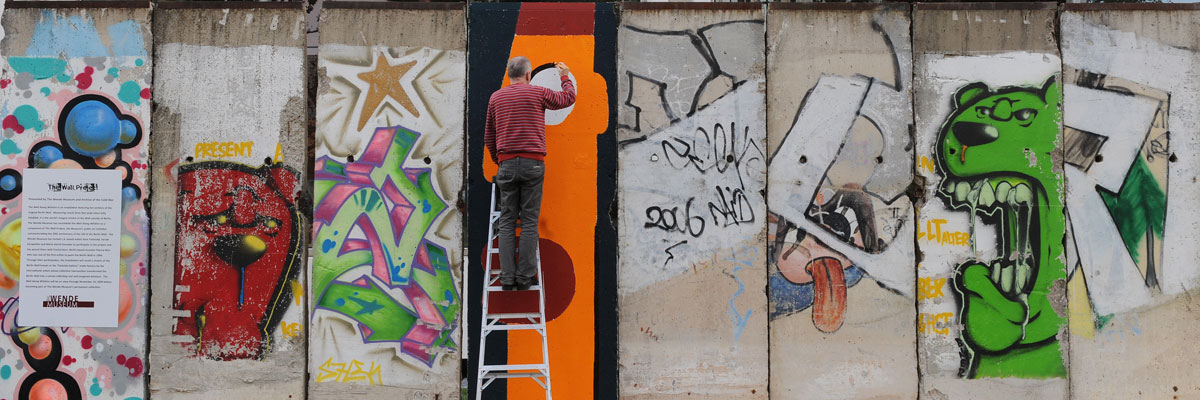 El artista francés Thierry Noir, que fue el primer artista en pintar sobre el muro de Berlín en 1984, da los últimos retoques a una sección que fue transportada a Los Ángeles para celebrar el vigésimo aniversario de la caída del muro. Mark Ralston/AFP/Getty Images