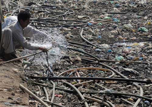 Pakistán: jóvenes paquistaníes llenan cubos con agua en una corriente de basura esparcidas en un barrio de Islamabad. El suministro de agua contaminada con elementos tóxicos es la principal causa del aumento de casos de enfermedades transmitidas por este medio.