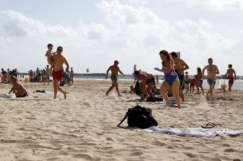 Un grupo de turistas busca refugio en una playa de Tel Aviv durante un ataque de misil lanzado por combatientes palestinos en la Franja de Gaza. (Gali Tibbon/AFP/Getty Images)