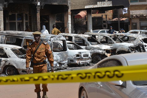 Un gendarme de Burkina Faso pasa a lado de coches quemados a causa de un atentado perpetrado por AQMI en Ouagadougou. Issouf Sanogo /AFP/Getty Images