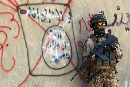 Un soldado iraquí permanece de pie junto a un eslogan de Daesh tachado. Ahmad Al Rubaye/AFP/Getty Images