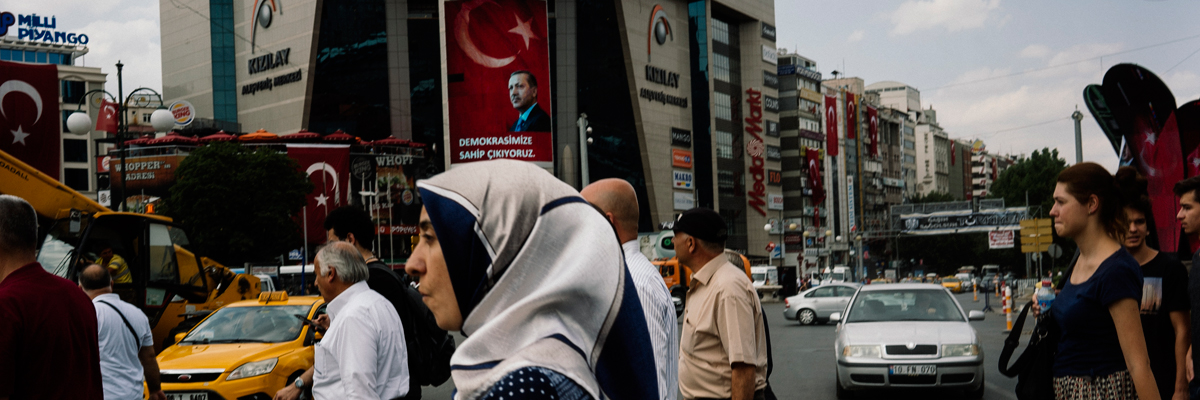 Gente camina cerca de un póster con la cara del Presidente turco, Recep Tayyip Erdogan, en la ciudad de Ankara. Dimitar Dilkoff/AFP/Getty Images