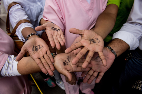Varias personas muestran las palmas de sus manos con el número asignado de la cola que hay fuera del supermercado para comprar comida, Caracas, 2015, Venezuela. Federico Parra/AFP/Getty Images