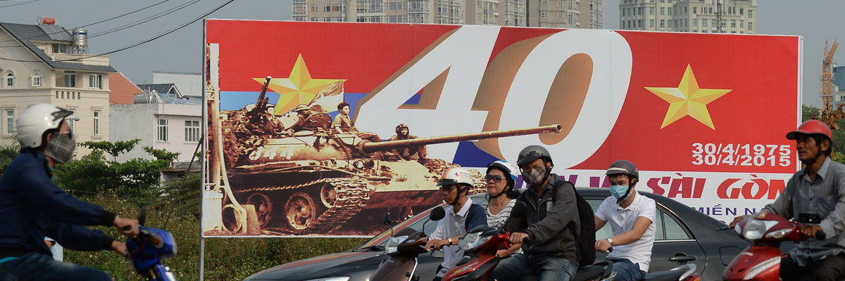Un grupo de motoristas pasan al lado de un cartel sobre el 40 aniversario de la caída de Saigón, actual ciudad de Ho Chi Minh, que supuso el final de la Guerra de Vietnam. HOANG DINH NAM/AFP/Getty Images