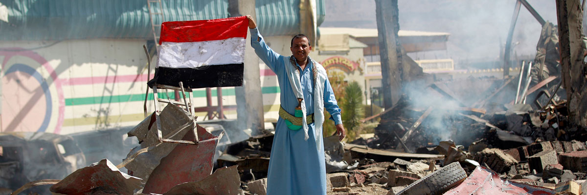 Un hombre yemení ondea una bandera en medio de las ruinas de un colegio bombardeado por la coalición liderada por Arabia Saudí en la capital Saná. Mohammed Huwais/AFP/Getty images 