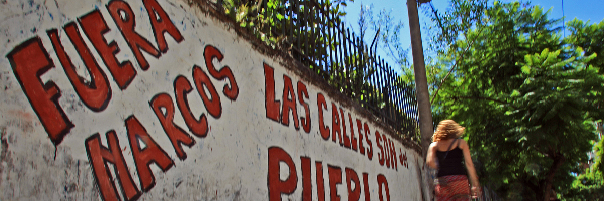 Una mujer pasa al lado de un muro con un grafiti que reza: "Fuera narcos. Las calles son del pueblo" (provincia argentina de Santa Fe. Carlos Carrión/AFP/Getty images