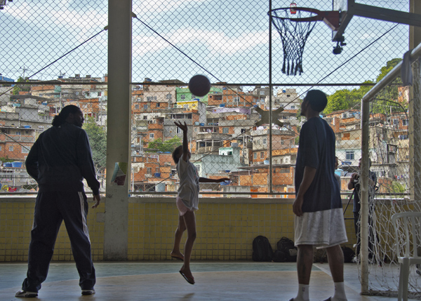 BALONCESTO: En el complejo de favelas de Alemao una niña juega al baloncesto con Nene, jugador de la NBA de origen brasileño. El complejo de Alemao es uno de los más inestables de Río de Janeiro. Situado en una zona estratégica, ocupa 200 hectáreas y se encuentra al norte de esta ciudad. En este complejo de favelas habitan alrededor de 400.000 personas. LIVIA VILLAS BOAS/Getty Images