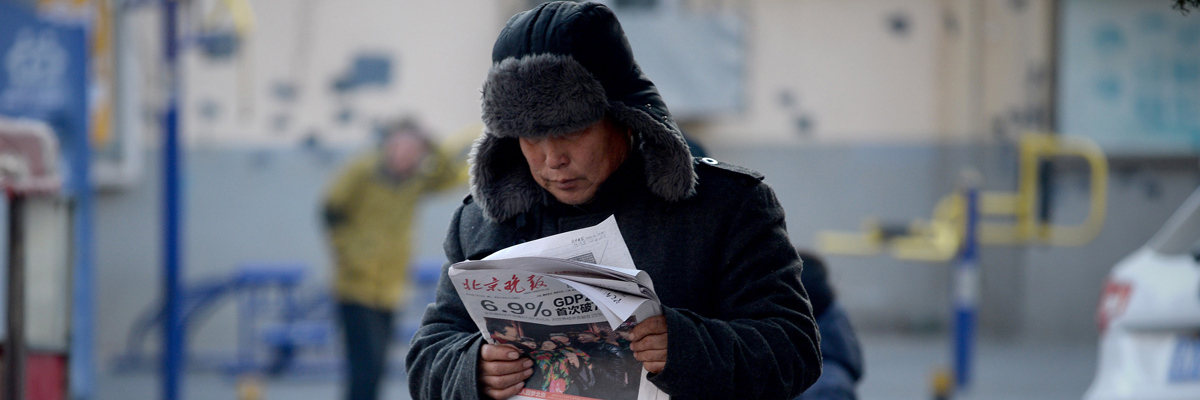 Un hombre pasea por Pekín con un periódico cuyo titular reza "El PIB de China crece un 6,9%". (Wang Zhao/AFP/Getty Images)