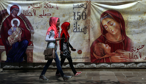 Mujeres musulmanas pasan delante de un cartel de la Virgen María en Beirut, Líbano. (Patrick Baz/AFP/Getty Images)