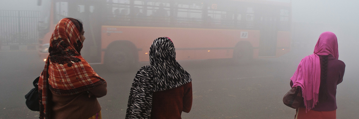 Mujeres esperan el autobús en Nueva Delhi ante una cortina de contaminación (PRAKASH SINGH/AFP/Getty Images)