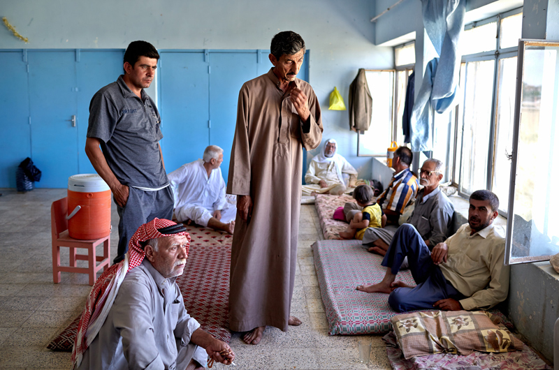 Los varones de una familia iraquí que huyó de Mosul, sentados en colchones y alfombras en una de las aulas de la escuela primaria de Alqosh en la que han encontrado cobijo. Fuente: ©ACNUR/UNHCR / S. Baldwin
