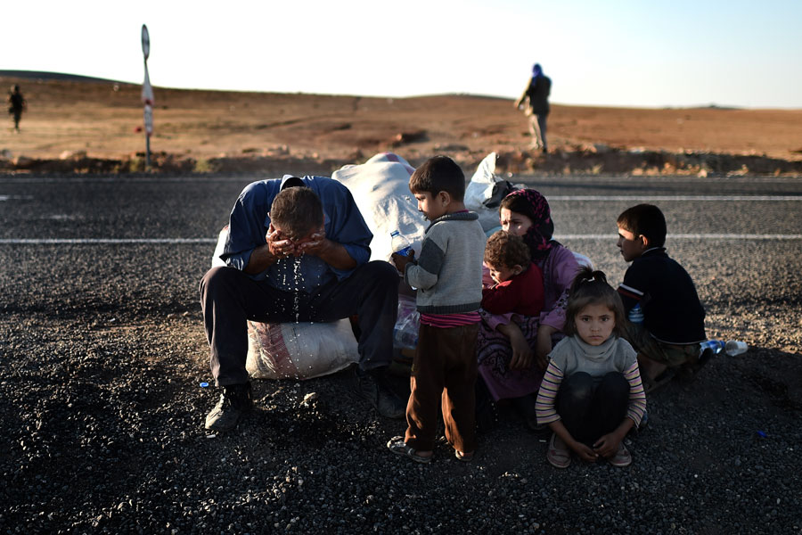 Éxodo masivo. Se calcula que alrededor de 150.000 kurdos sirios han abandonado la ciudad de Kobane y otros pueblos de la zona para alcanzar suelo turco en las últimas semanas, engrosando así las filas de refugiados sirios en Turquía: unos 1,4 millones de personas, pero algunas fuentes no oficiales hablan de una cifra superior a los dos millones. En la foto, refugiados sirios sentados en un carretera de la ciudad turca de Suruc tras haber cruzado la frontera huyendo del avance del Estado Islámico, 5 de octubre de 2014. Aris Messinis /AFP/Getty Images.