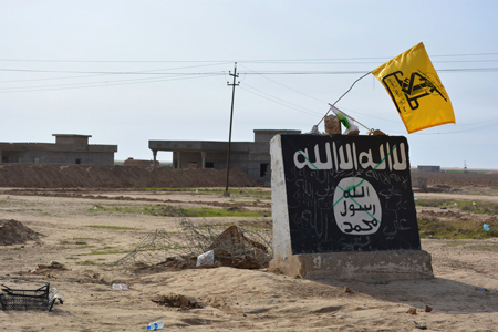 Bandera amarilla de una milicia chií sobre un muro con el emblema del Estado Islámico. Younis Al Bayati/AFP/Getty Images