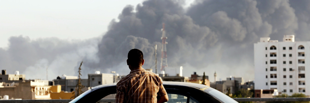 Un hombre en Trípoli mira la cortina de humo que ha dejado la explosión de un depósito de gasolina cuasado por los enfrentamientos de las milicias en la ciudad. (AFP/Getty Images)