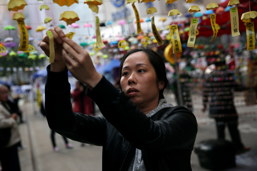 Protestas en Hong Kong: Las protestas pro democracia de la Revolución de los Paraguas toman las calles de Hong Kong entre el 22 de septiembre y el 15 de diciembre. En la imagen, una manifestante cuelga paraguas de papel durante una protesta en el distrito de Causeway Bay el 12 de diciembre. Isaac Lawrence/AFP/Getty Images.