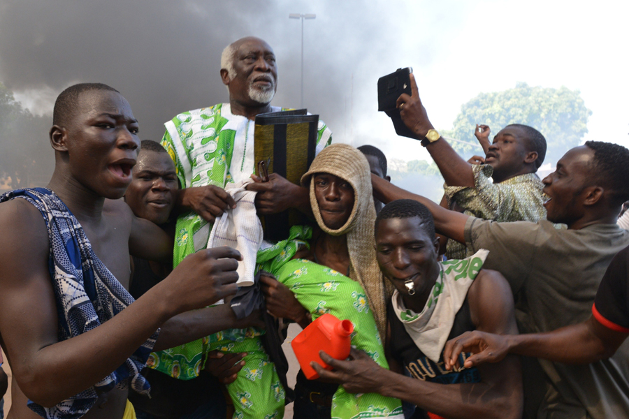 Burkina Faso: El 17 de noviembre se decide que el civil Michel Kafando presidirá Burkina Faso, tras el golpe de Estado llevado a cabo por el Ejército el 31 de octubre que hizo dimitir a Blaise Compaoré, presidente del país desde 1987. En la imagen, partidarios de la oposición llevan a hombros a un parlamentario opositor mientras sale humo del Parlamento en Uagadugú el 30 de octubre. Issouf Sanogo/AFP/Getty Images.
