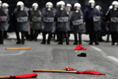 Unas banderas rojas yacen delante de fuerzas antidisturbios tras una manifestación contra las medidas de austeridad en Atenas, el 2 de diciembre de 2010. (AFP/Getty Images)