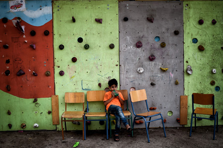 Un niño sirio sentado en una escuela abandonada que sirve como refugio para familias en Atenas, Grecia. (Aris Messinis/AFP/Getty Images)