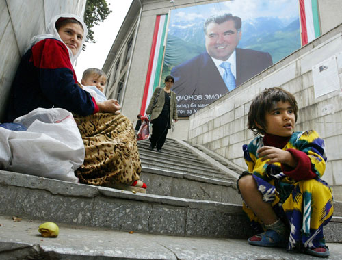 Una madre con sus hijos mendiga en las calles de la ciudad de Dusambé. Al fondo, la imagen del presidente de Tayikistán, Emomali Rakhmonov. Vyacheslav Oseledko/AFP/Getty Images