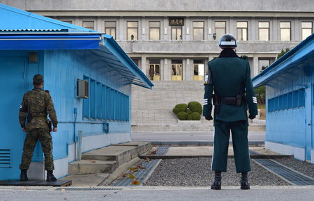 South Korean soldiers stand guard as a North Korean soldier (C back) is seen at the truce village of Panmunjom in the Demilitarized Zone dividing the two Koreas on November 12, 2014. Under growing pressure at the United Nations over its human rights record, North Korea has accused rival South Korea of its own "crimes against humanity" over the Sewol ferry tragedy. AFP PHOTO / JUNG YEON-JE (Photo credit should read JUNG YEON-JE/AFP/Getty Images)
